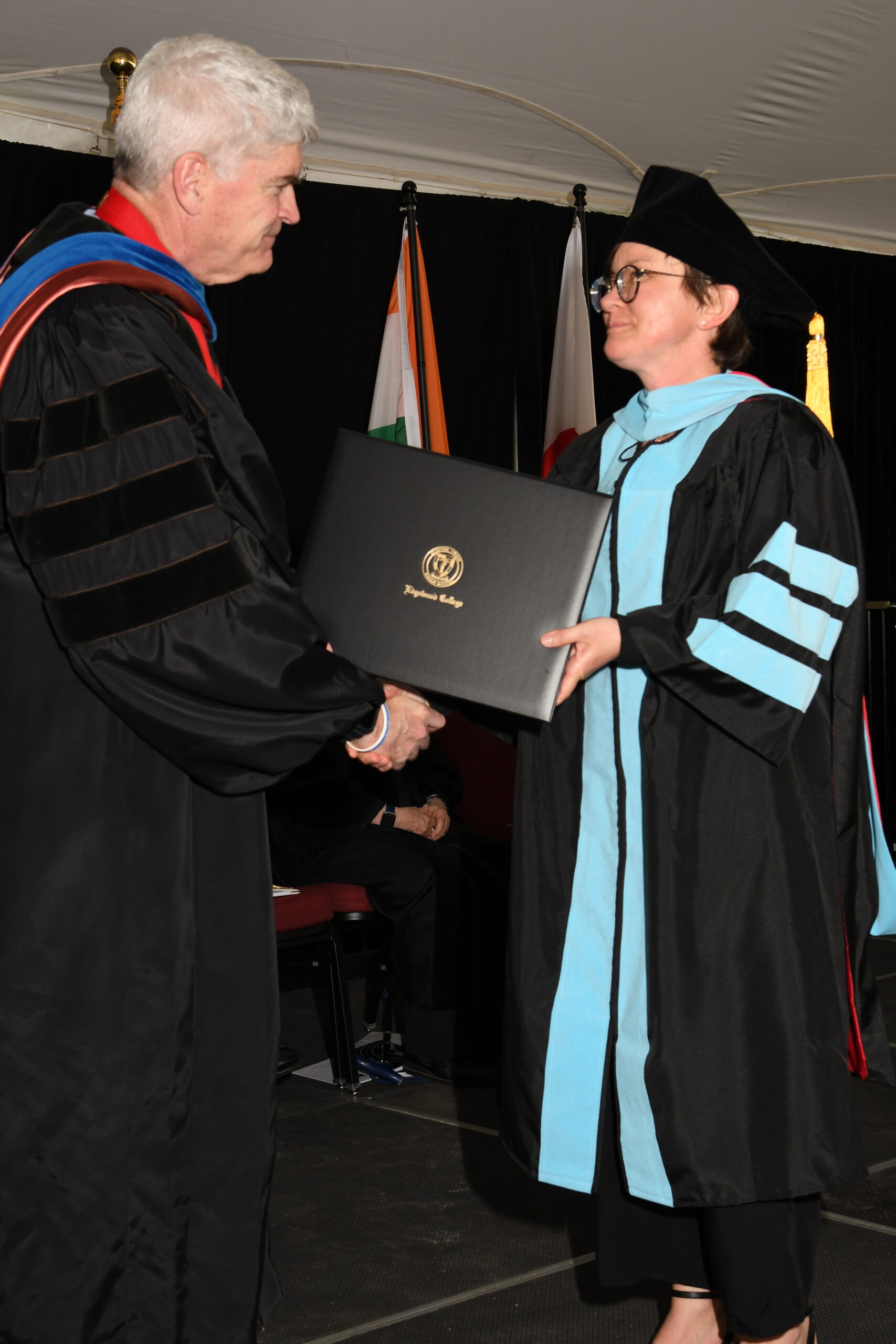 Woman walking across stage with shaking hands with man.