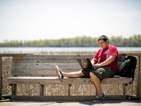 student outside working on a laptop