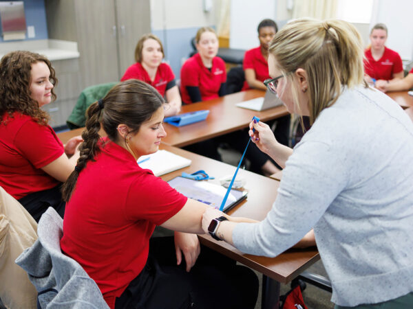 a person in a red shirt sitting at a table with other people in the background