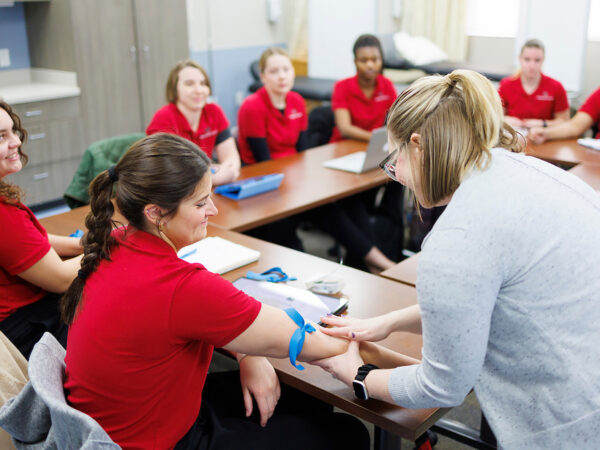 a person in a red shirt talking to a group of people