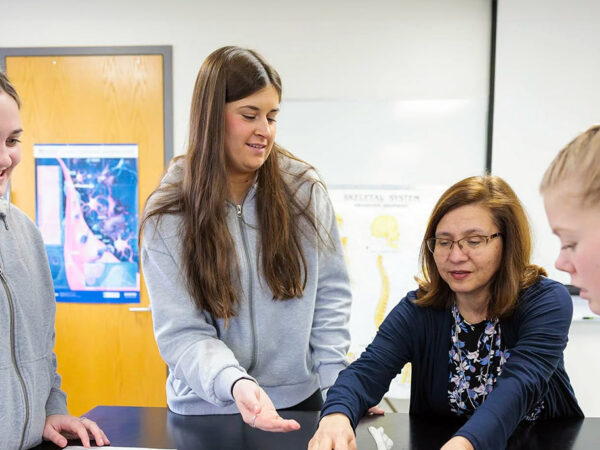 three students collaborating with a professor