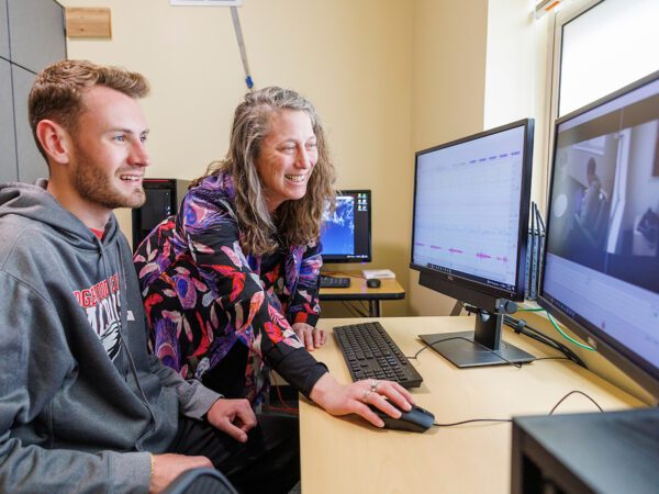 a person and person sitting at a desk with computers