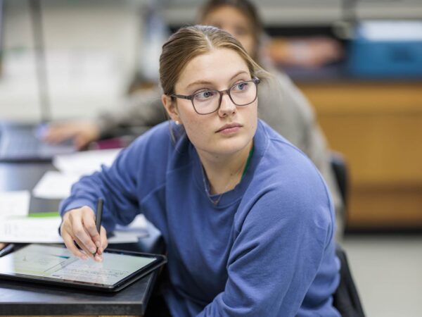 student writing on a tablet