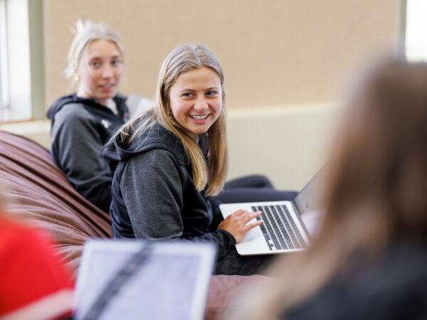 a person smiling while holding a laptop