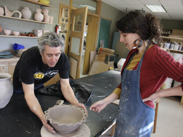 a person and person working on a pottery wheel