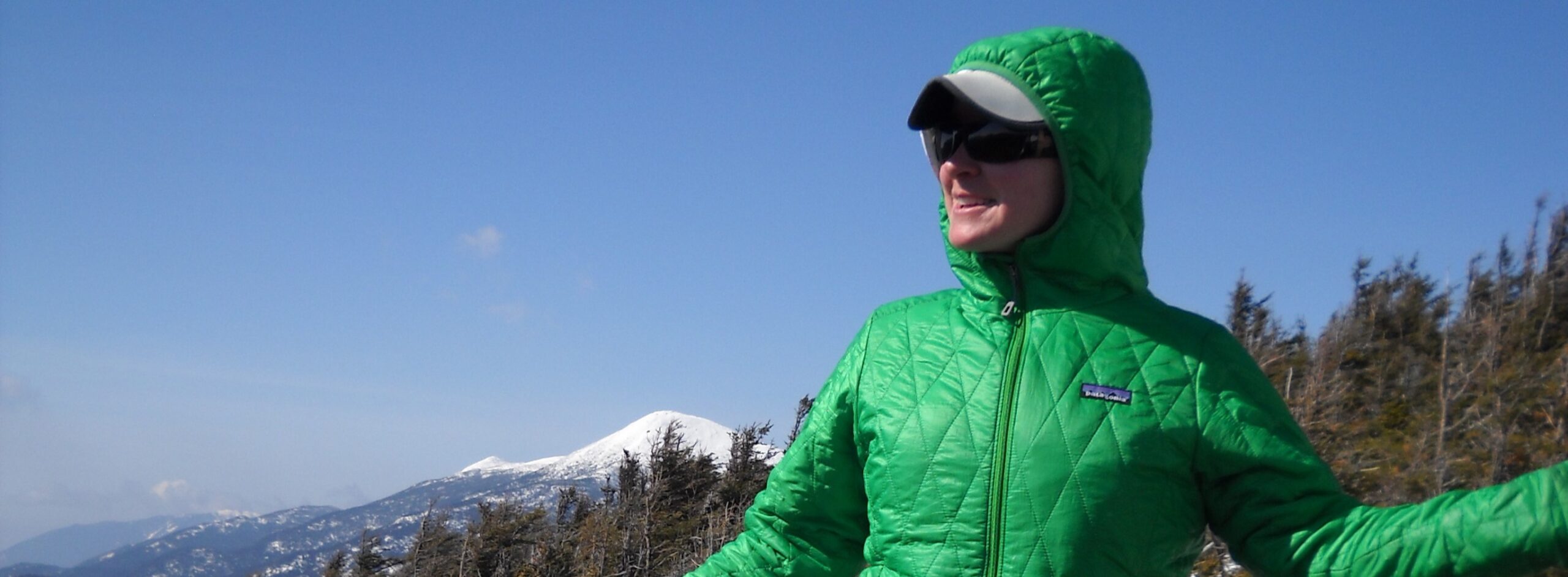 Woman looking over mountain cliff in winter gear.